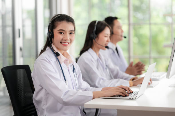 asia medical service team health advice online. smiling face stood wearing the headphones with a microphone and stethoscope in clinics.concept of remote medicine, health care call center online. - healthcare and medicine laboratory senior adult analyzing imagens e fotografias de stock