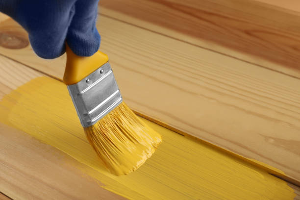 istock Worker applying yellow paint onto wooden surface, closeup. Space for text 1327426596