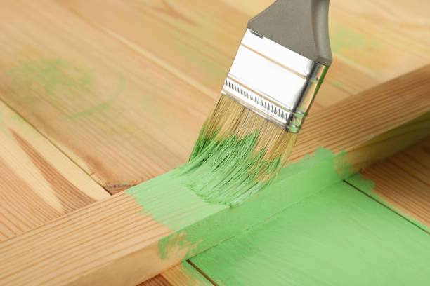 istock Applying green paint onto wooden surface, closeup. Space for text 1327426669