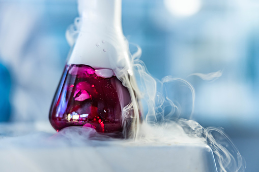 Close up of chemical reaction of a purple liquid in a beaker while heating on a magnetic stirrer in laboratory.