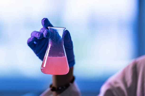 Close up of unrecognizable scientist examining beaker with antiviral drug in laboratory. Copy space.