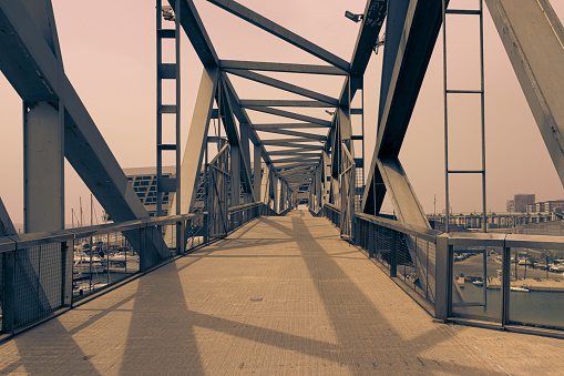 Perspective view of the bridge that hangs over the Port of the Forum, Barcelona, of metallic structure and used by pedestrians, cyclists, runners and sportsmen in general.