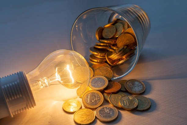 istock Light bulb lit with glass full of coins next to it. 1327431125
