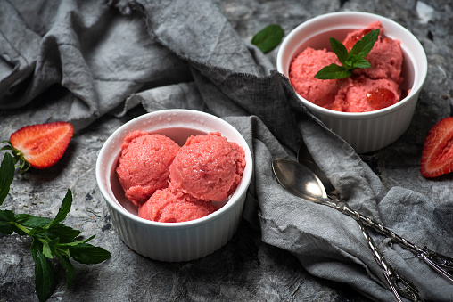 Homemade strawberry fruit ice cream balls served in a cup table top view. Cold and refreshing organic dessert for the summer