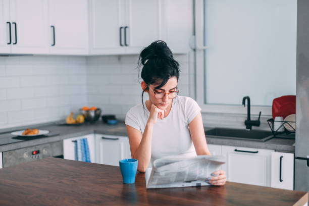 piękna młoda kobieta w kuchni - reading newspaper break tea zdjęcia i obrazy z banku zdjęć