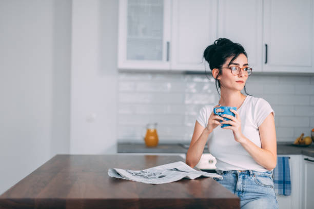 hermosa mujer joven en la cocina - reading newspaper break tea fotografías e imágenes de stock