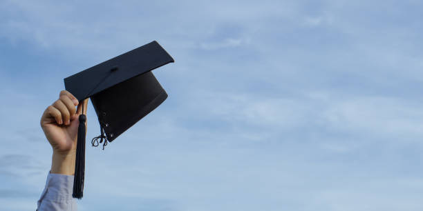 istock Graduation day,Mortar board in hand with sky background, Happiness feeling,Congratulation. 1327434223