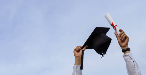 istock Graduation day,A certificate and a mortar board in hand with sky background, Happiness feeling,Congratulation. 1327434234