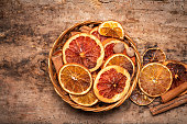 Dried sliced orange and grapefruit fruit slices in a wicker bowl tabletop view