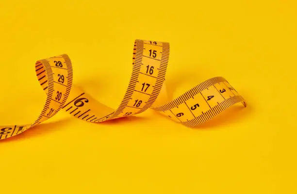 Measuring tape on yellow background