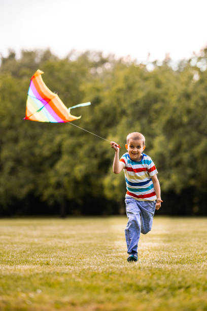 istock Little boy running whit kite in the public park 1327436794