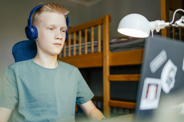 Student watching lesson online Young student watching lesson online on laptop and studying at home. dorm bunk beds stock pictures, royalty-free photos & images