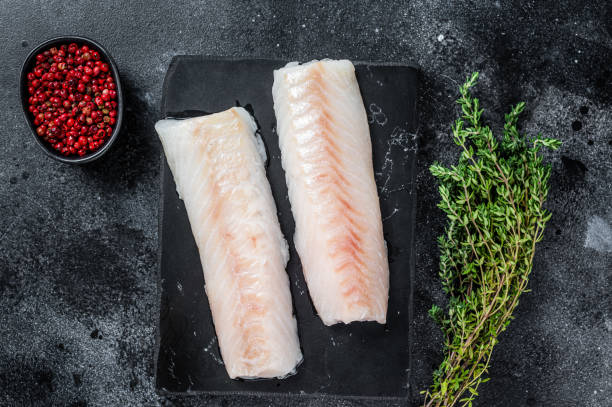 istock Raw cod loin fillet fish on marble board. Black background. Top view 1327440907