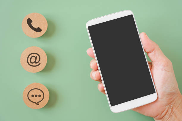 istock hand holding white mobile phone with clipping path on touchscreen and blurred brown contact method paper, contact us, call, mail or chat, question and answer ,new normal lifestyle , social distancing 1327440973