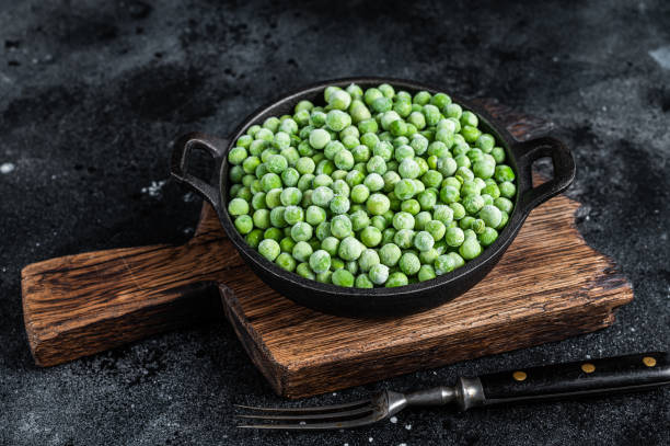 istock Fresh Frozen green peas in a pan. Black background. Top view 1327442016
