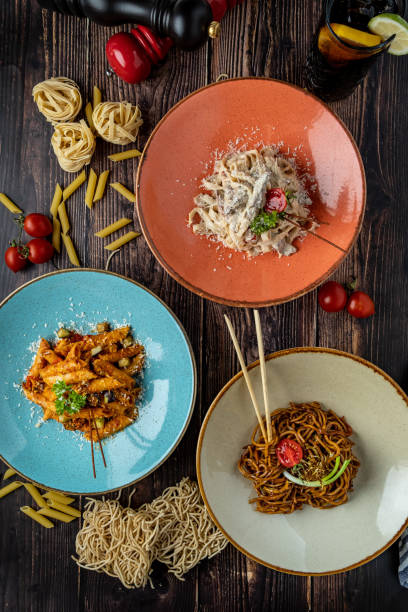 лапша, феттуччине и паста пенне на трех отдельных тарелках на деревянном фоне. - szechuan cuisine стоковые фото и изображения
