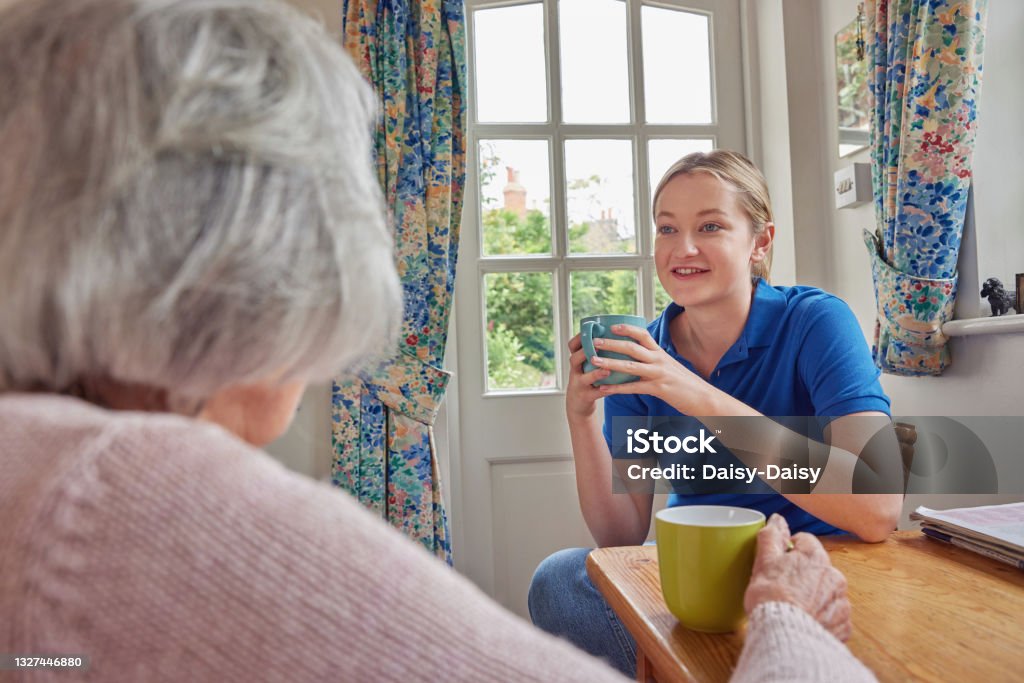 Weibliche Haus hilfe mit Tasse Tee mit einsamen Senior Frau in der Küche - Lizenzfrei Sozialarbeit Stock-Foto