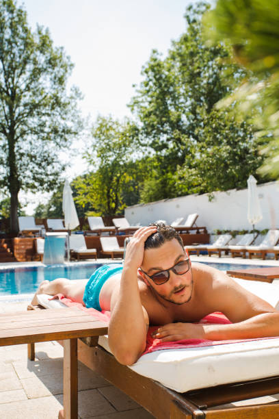 istock Man lying on the sunbed by the swimming pool 1327447175