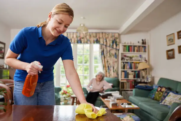 Photo of Female Home Help Cleaning House And Talking To Senior Woman