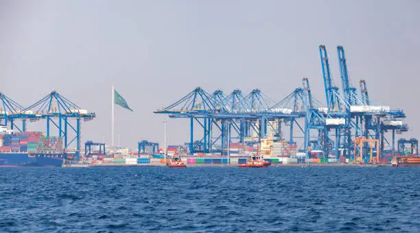 Gantry cranes unload container ships on a sunny summer day. Jeddah port, Saudi Arabia