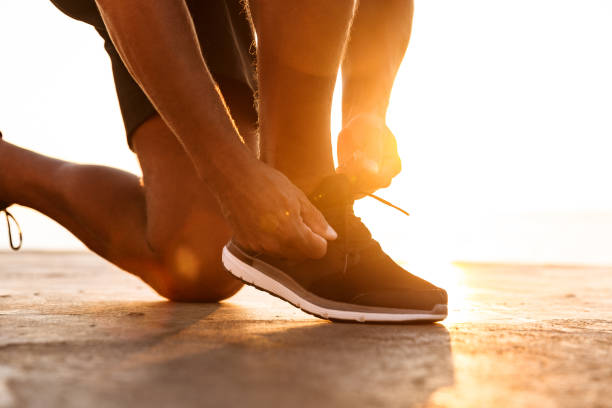 close up of a sportsmantying his shoelaces - shoe tying adult jogging imagens e fotografias de stock