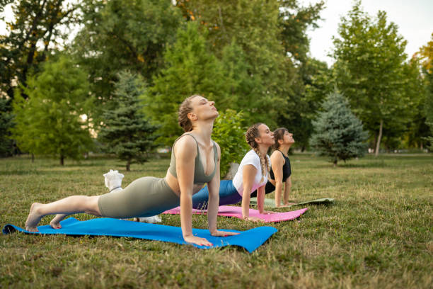 istock Three young women practicing yoga at public park 1327451301