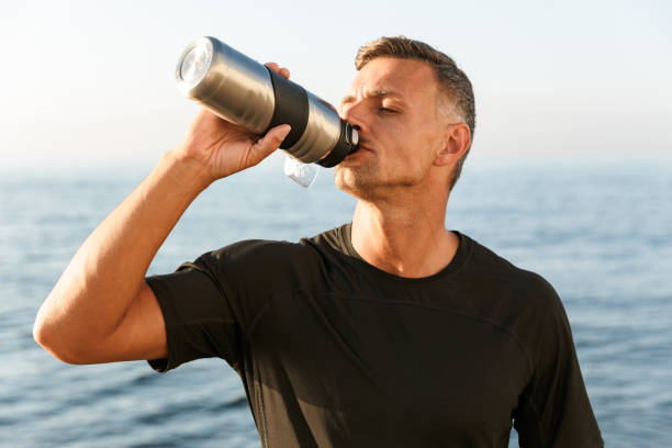 istock Handsome strong mature sportsman drinking on the beach. 1327451705