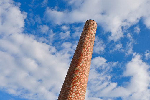 tall chimney old red bricks in an old factory. smoke stack An old brick chimney against a blue sky.
