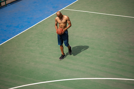 Break, rest. Strong athlete african-american male basketball player training at street public stadium, sport court or palyground outdoors. Concept of healthy active lifestyle, motion, hobby. Top view