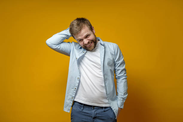 istock Handsome, shy Caucasian man with a beard cute smiling, holds hand behind head and squinted modestly, looking to the side. 1327460627