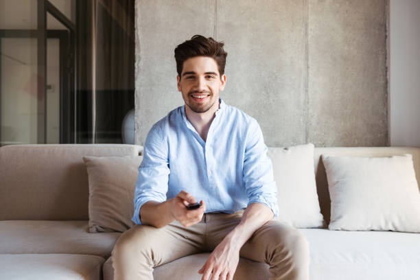 istock Smiling young man holding TV remote 1327466901