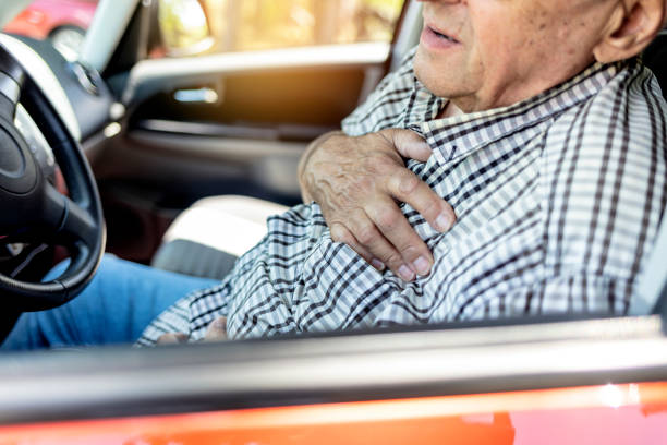 старший старик, страдающий от сердечного приступа в машине. - human hand help pain heart attack стоковые фото и изображения