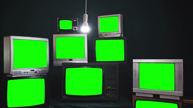 Nine Vintage Televisions turning on Green Screens on a Retro TV Wall. Dark Tone. Zoom In. 4K Resolution.