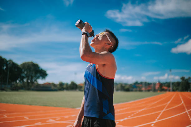 male sport athlete with sunglasses drinking water at all-weather-track and field stadium in the morning Confidence male sport athlete with sunglasses drinking water at all-weather-track and field stadium in the morning asian drinking water stock pictures, royalty-free photos & images