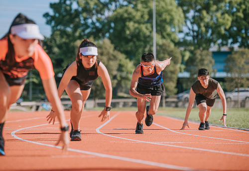 Jóvenes atletas chinos asiáticos corren corriendo en pista y corren hacia la línea de meta por la mañana en el estadio de atletismo photo