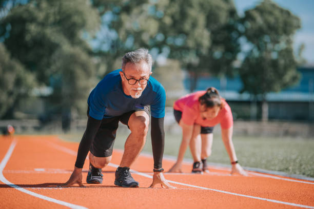 asiatische chinesische senior paar immer bereit, im leichtathletik-stadion am morgen zu sprinten - senior adult healthy lifestyle athleticism lifestyles stock-fotos und bilder