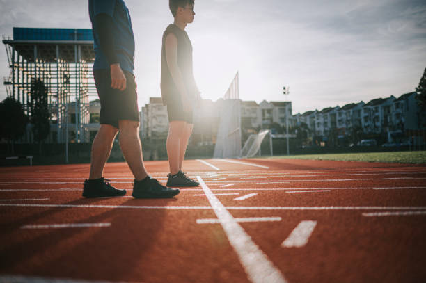 Asian chinese senior athletes father and son lining up getting ready starting line running at track and run towards finishing line in the morning at track and field stadium