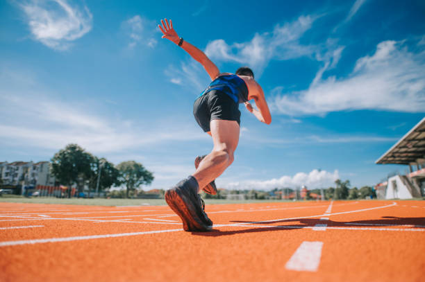 vue arrière aérodynamique les athlètes masculins chinois d’asie sprintent en courant sur piste et courent vers la ligne d’arrivée le matin au stade d’athlétisme - athlete sport starting line muscular build photos et images de collection