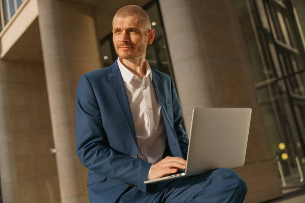 istock A young attractive businessman is typing a letter on his laptop, looking away, while thinking what to  type 1327477453