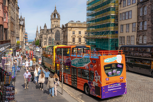 Edinburgh, Scotland - Pedestrians passing tour buses and souvenir shops on the Royal Mile, in the heart of Edinburgh's historic Old Town.