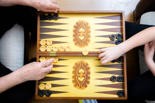 バックギャモンを演奏するおじいちゃんと孫の手 - backgammon ストックフォトと画像