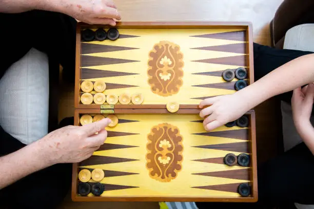 Hands of grandpa and grandson playing backgammon
