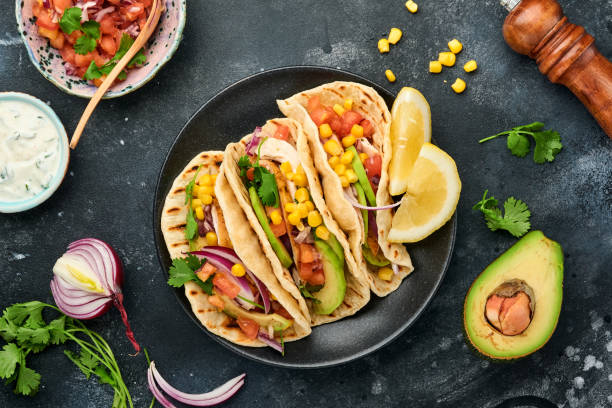 istock Mexican tacos with grilled chicken, avocado, corn kernels, tomato, onion, cilantro and salsa at black stone table. Traditional Mexican and Latin american street food. Top view. 1327481856