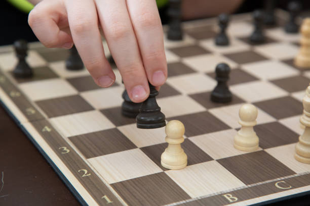 istock Hands of little boy playing chess. 1327482000