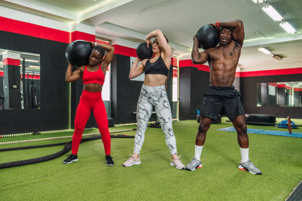 istock Three multiracial bodybuilder athletes doing toning exercises with weight ball in a gym. Two African bodybuilders and a Caucasian bodybuilder doing gym workout routine. 1327482739