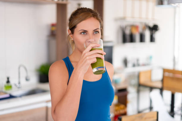 hermosa mujer bebiendo un jugo de desintoxicación verde - apple women green eating fotografías e imágenes de stock
