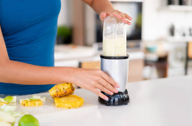 nahaufnahme auf eine gesunde essende frau mit einem mixer, um einen smoothie am morgen zu machen - juicer food and drink healthy eating sport stock-fotos und bilder