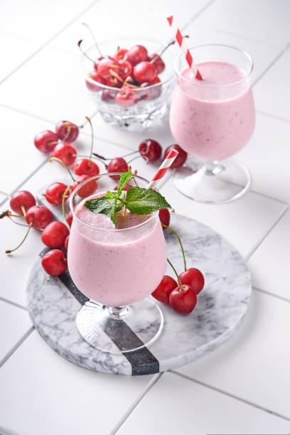 rosa kirsche smoothies mit frischen roten beere, chia-samen, mintgrüne blätter, weißen stein küche hintergrund. selektiver fokus. - healthy lifestyle cranberry healthy eating milk shake stock-fotos und bilder