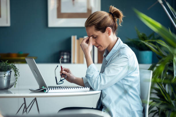 istock Exhausted mature woman with headache while working with computer in living room at home. 1327483863