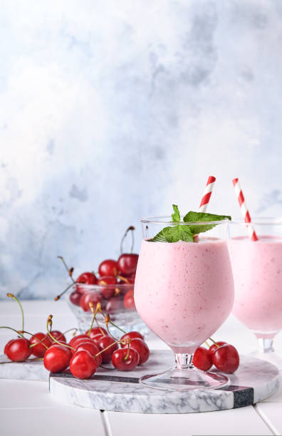 rosa kirsch-smoothies mit frischen roten beeren, chiasamen, minzgrünen blättern, weißem stein küchenhintergrund. selektiver fokus. - healthy lifestyle cranberry healthy eating milk shake stock-fotos und bilder